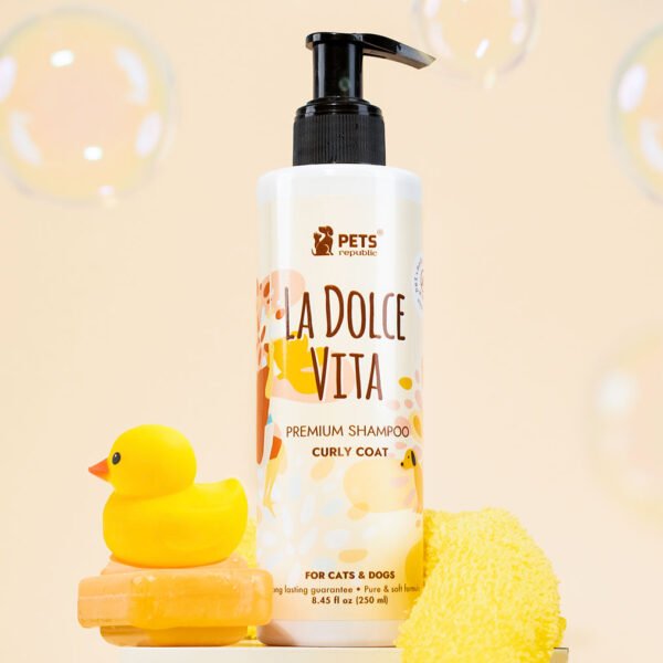 Pets Republic Curly Coat Tearless Shampoo bottle with La Dolce Vita branding, alongside a rubber duck and yellow sponge, set against a soft peach background with bubbles