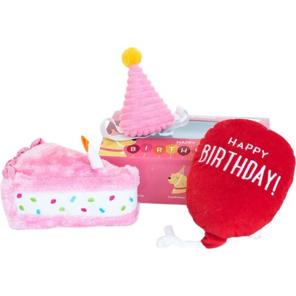 Three plush toys from ZippyPaws: a slice of cake with pink icing and sprinkles, a pink party hat with a yellow pom-pom, and a heart-shaped toy with “HAPPY BIRTHDAY!” text, displayed against a white background.