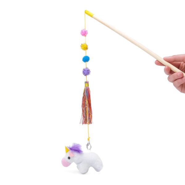 A hand holding a wooden stick with a string attached to a small plush unicorn toy, featuring colorful balls and a tassel.