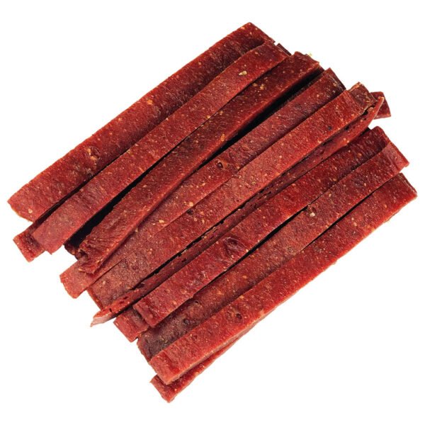 Close-up view of Dog Fest Meat Slices with Venison, showcasing the texture and color of the beef jerky strips arranged on a white background.