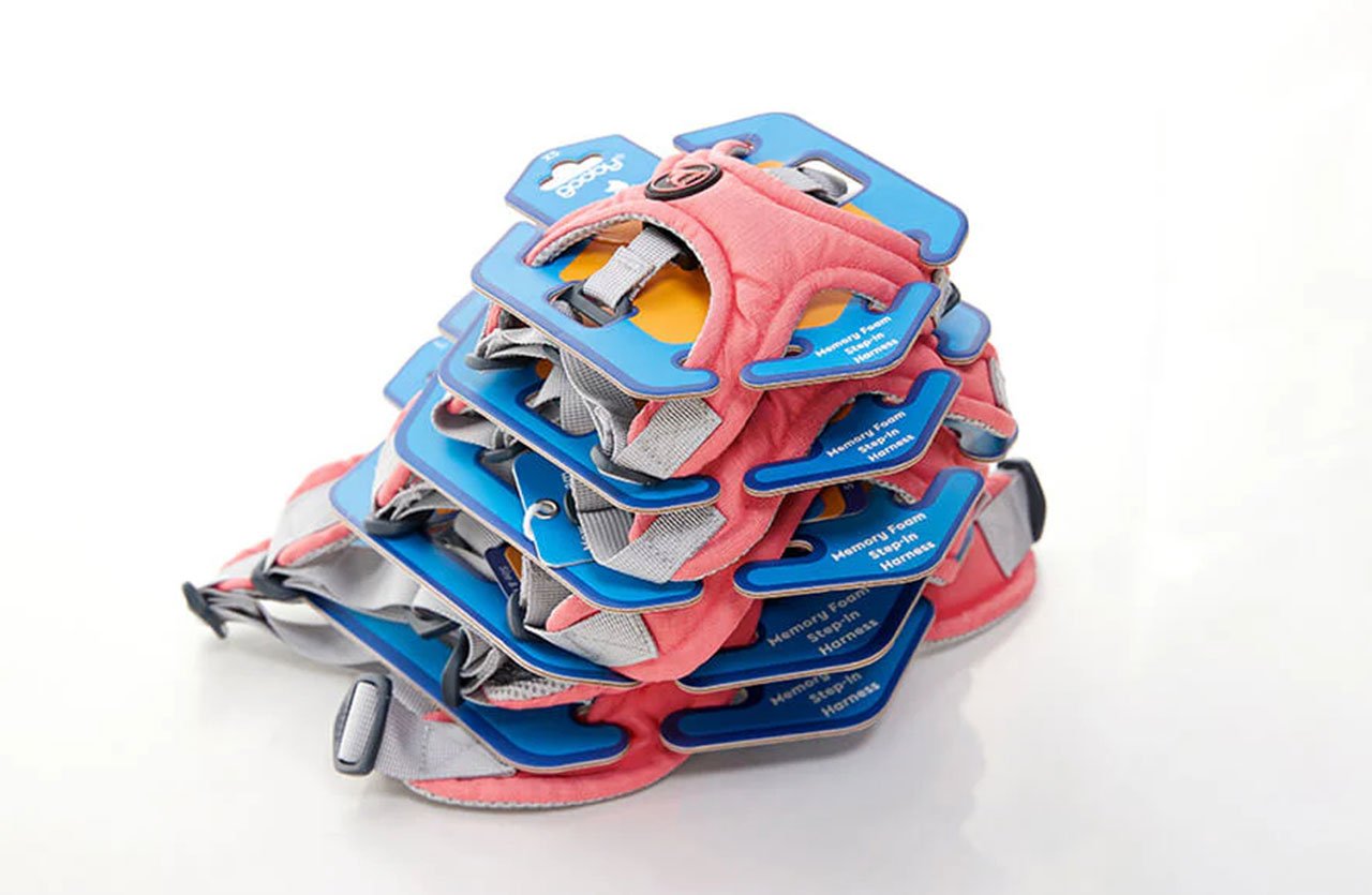 A stack of small-sized dog harnesses in various colors, including blue and pink, designed for tiny dog breeds.