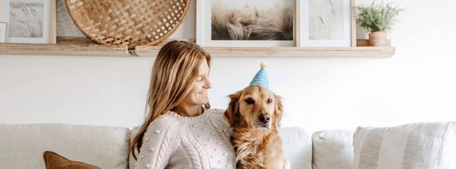 Golden retriever wearing a birthday hat sitting beside a child on a woman in a cozy home setting