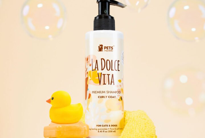 Pets Republic Curly Coat Tearless Shampoo bottle with La Dolce Vita branding, alongside a rubber duck and yellow sponge, set against a soft peach background with bubbles
