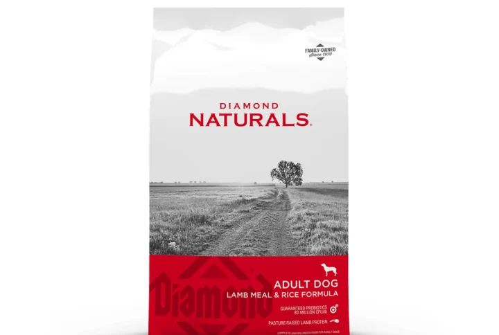 Studio shot of the Diamond Naturals Adult Dog Lamb Meal & Rice Formula bag. The design features a white top section with a black-and-white rural landscape and a vibrant red bottom section with key nutritional claims, including "Pasture-Raised Lamb Protein" and "Guaranteed Probiotics 80 Million CFU/LB."