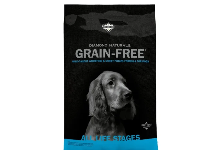 Studio shot of the Diamond Naturals Grain-Free Wild-Caught Whitefish & Sweet Potato Formula for Dogs bag. The design features a matte black background with a black-and-white Irish Setter portrait and a bright cyan blue bottom band with "All Life Stages" text.