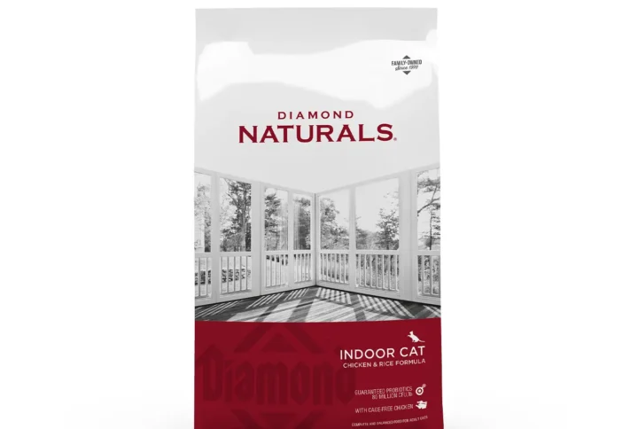 Studio shot of the Diamond Naturals Indoor Cat Chicken & Rice Formula bag. The design features a white top section with an interior-perspective landscape and a deep red bottom section with key nutritional claims, including "Cage-Free Chicken" and "Hairball Control."