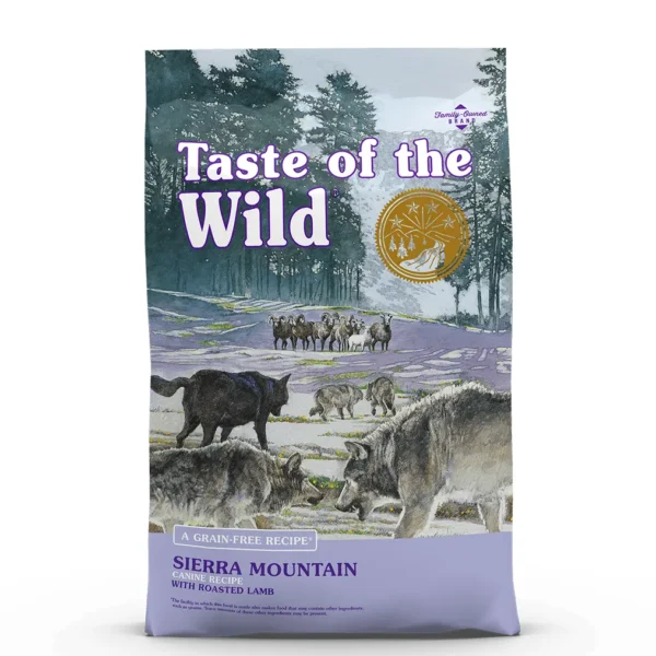 Studio shot of the front of the Taste of the Wild Sierra Mountain Canine Recipe bag. The predominantly purple/lavender bag displays a wilderness scene with pine trees, hazy mountains, grazing sheep, and a pack of wolves (with a prominent large grey wolf in the foreground). Key texts include "SIERRA MOUNTAIN CANINE RECIPE," "WITH ROASTED LAMB," and "A GRAIN-FREE RECIPE," along with a gold circular emblem and small print "Family-Owned BRAND."